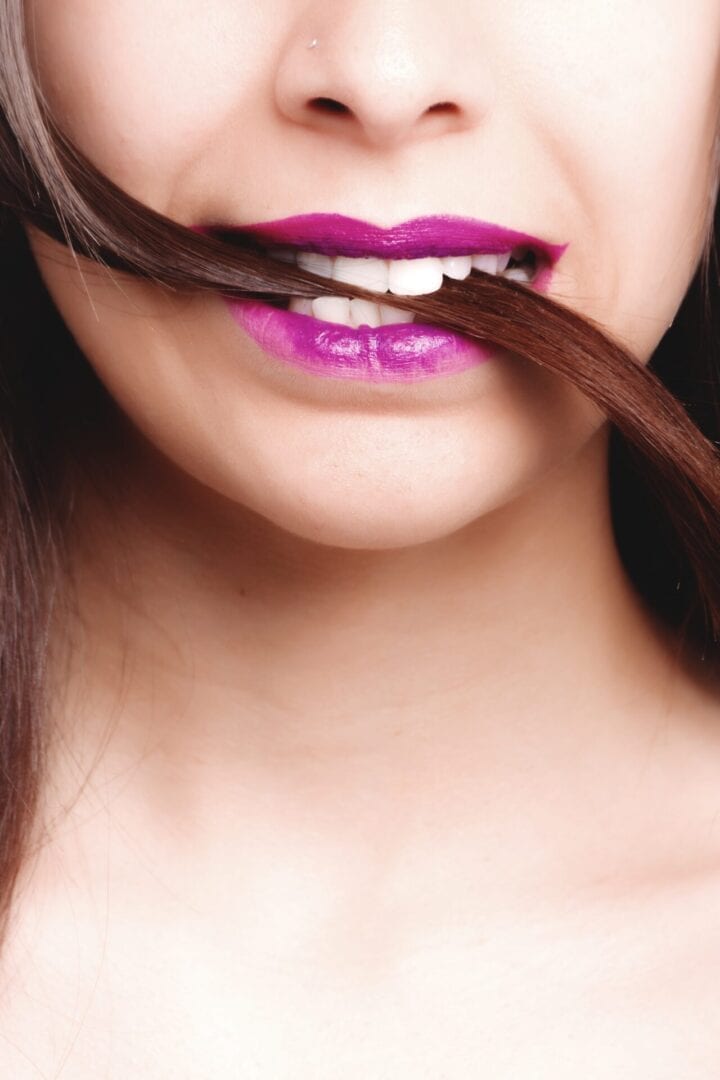 A woman with purple lipstick and brown hair.