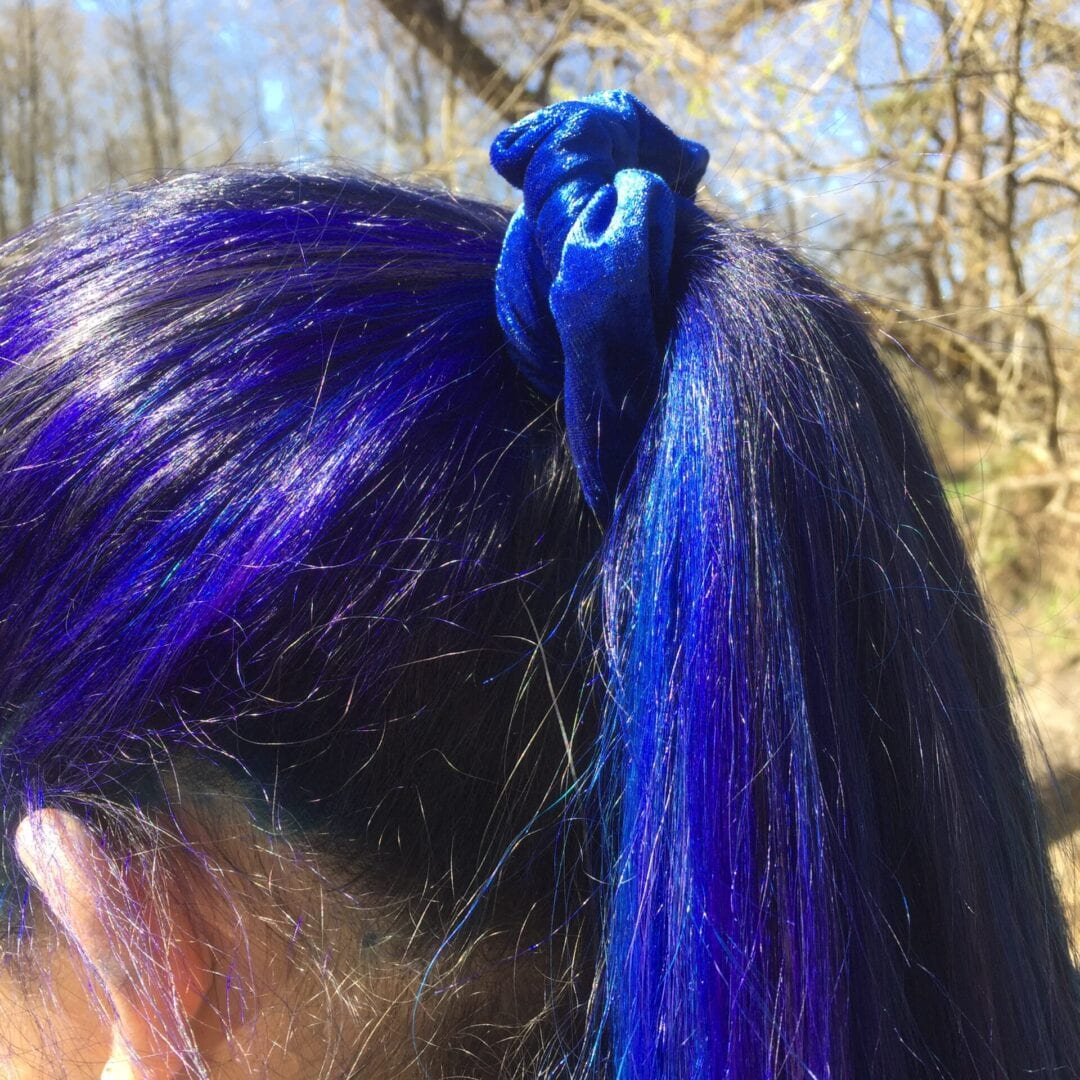A woman with blue hair is wearing a ponytail.